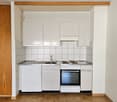 Small kitchen with white cabinets, tiled backsplash, electric stove, and dishwasher
