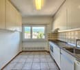 Spacious kitchen with tile flooring, white cabinets, and a large window providing a scenic view of the surrounding area.