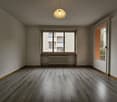 Spacious living room with hardwood flooring, large windows, and a decorative pendant light fixture. The room appears to be in a residential apartment or condominium setting.