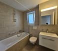 White modern tiles, bathtub, toilet, sink, mirror