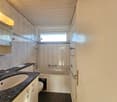 Bathroom with tiled walls, bathtub, sink with mirror, toilet, and towel rack.