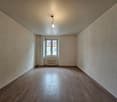 Empty room with wooden floor, white walls, large window, light fixture, white radiator