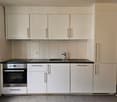 white cabinets, black countertops, oven, stainless steel sink, refrigerator, electrical outlet