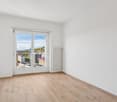 empty room, wooden floor, white walls, sliding doors to balcony, window to view