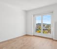 Empty room with wooden floor, sliding door, balcony, radiator, large window