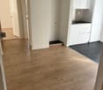light wood flooring, neutral color walls, white cupboards, power outlet