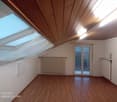 empty room, wooden floor, white walls, radiator, double windows, sloped ceiling, skylight
