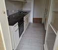 Open kitchen with stove, oven, sink, kitchen cabinets, floor outlet, tiled floor, white doors