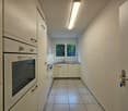 White cabinets, tiled floor, stainless steel sink, oven and dishwasher, window