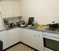 kitchen area with white cabinets, countertop, sink, stove and oven, dishwasher, appliances and utensils