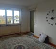 white walls, large window, carpet, heater, clock, small pillow