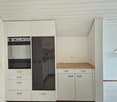 white cabinetry, black oven, stainless steel countertop, white tiles, white drawers, electrical outlet