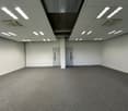 large room with gray carpet, white walls, ceiling lights, two doors
