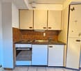 compact kitchen, tile flooring, small sink, two-burner stove, white cabinets, refrigerator
