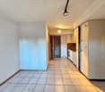 Empty room, tiled floor, white walls, kitchen area with cabinets and appliances