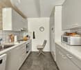 white cabinetry, stainless steel sink, silver appliances, tiled walls, tiled flooring