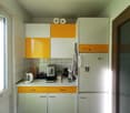 modern kitchen with white and yellow cabinets, coffee machine, kettle, refrigerator, countertop