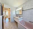 Bathroom with double sink, mirror, bathtub, and radiator