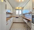 modern kitchen with white cabinets, wooden countertops, tiled floor, dishwasher, washing machine, sink, and a window