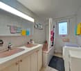 Bathroom with sink, bathtub, toilet, shelves, and washing machine.