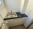 compact sink, white cabinets, tiled walls, floor heater