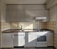 Kitchen with a sink, faucet, stove, dishwasher, and oven, with wooden and tiled walls and cabinets