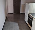 Modern kitchen with white cabinets, tiled floor, wooden ceiling, white walls, built-in oven, and a radiator