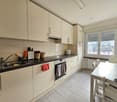 Modern kitchen with white cabinets, black countertops, stainless steel appliances, and a window with view