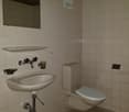 Bathroom: white tiled wall, toilet, sink, mirror, soap dish, tissue holder