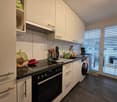 modern kitchen with white cabinets, black countertops, black stove, dishwasher, washing machine, large windows