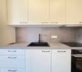 modern kitchen with white cabinets, gray countertops, black sink, black stove, and a dishwasher