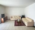 Empty room, tiled floor, two couches, glass coffee table, television, rug, side tables, wooden cabinet
