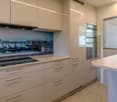 modern kitchen with white cabinetry, granite countertop, stainless steel appliances, decorative wall art, white backsplash