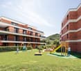 modern apartment complex with multiple balconies, playground for children, lush grass