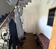 an entrance hall with a staircase, clothes hanging, shoes on the bench, white door, chalkboard