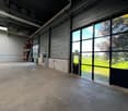 Empty room with concrete floor, metal ceiling, large windows, and a door leading to an outdoor area.