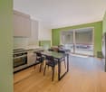 kitchen and dining area, wooden floor, green walls, kitchen appliances, dining table and chairs, sliding door, couch