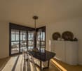 large window with balcony access, dining table, chairs, chandelier, cabinet, picture frames