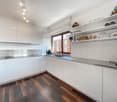 white kitchen, wooden floor, stainless steel counter, white cabinets, window, sink, faucet