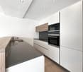 modern kitchen with white cabinets, wooden countertop, granite countertop, integrated appliances, under cabinet lighting