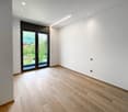 Empty room with white walls, wooden floor, sliding glass door, and outdoor view