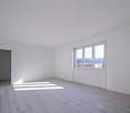 empty room with white walls, wooden floor, large window, doorway