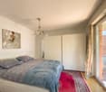 White bed, white wardrobes, floor lamp, painting, carpet, double glass door to balcony