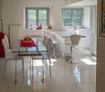 dining room, glass table, white chairs, kitchen island, white tile floor, windows, natural light