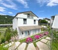 2 story house, white walls, brown roof, balcony, garden, beautiful view of the mountains