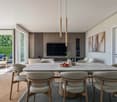 Dining room with large table, chairs, TV, wooden floor, sliding glass door, balcony, plants, artwork