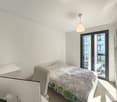 white walls, bed, desk, monitor, chair, sliding glass door, balcony