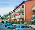 Apartment building, multiple floors, balconies, parking area, multiple cars parked