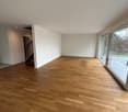 large room with hardwood floors, white walls, glass sliding doors leading to balcony, staircase on the left side