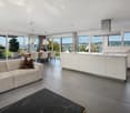 open plan living/dining area, modern kitchen, large windows, dining table, sofa, view of the lake